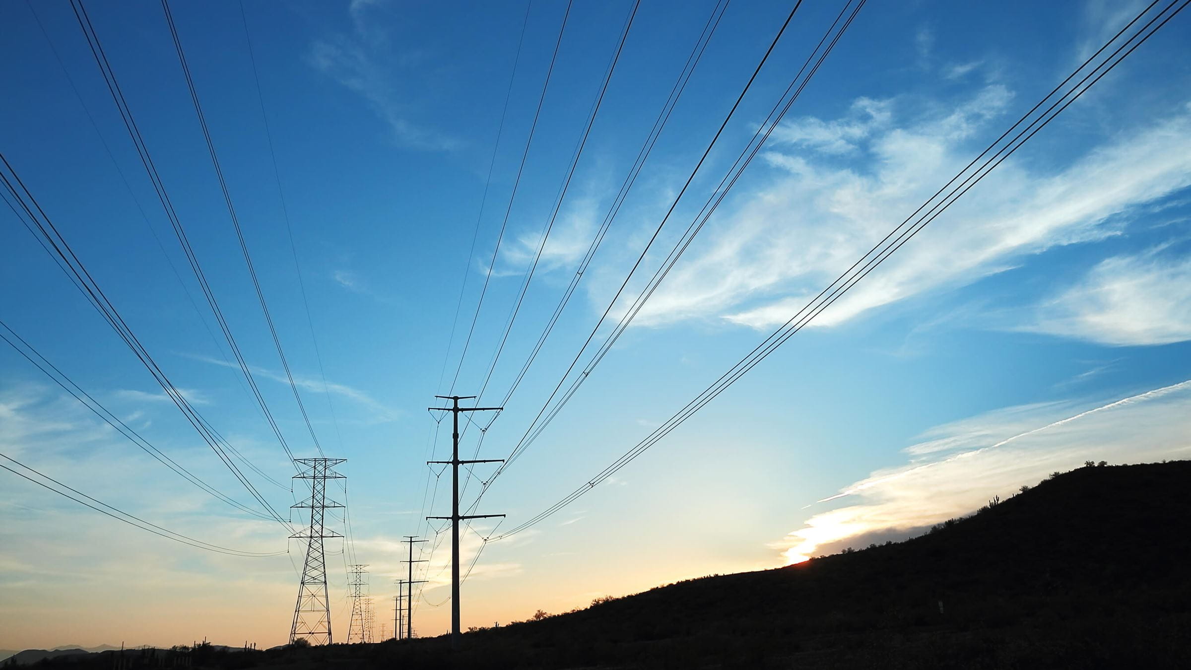 Transmission towers and power lines at sunset
