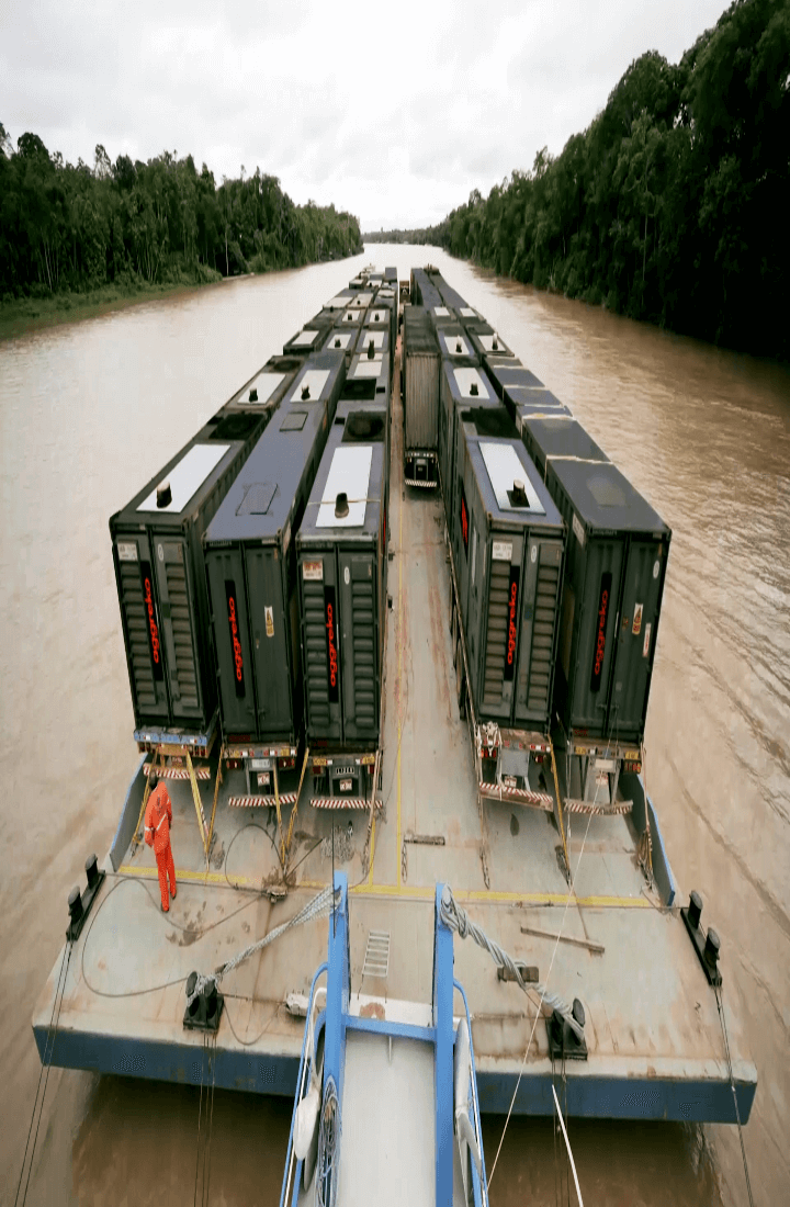 Mobile version of image of boat carrying generators up river.