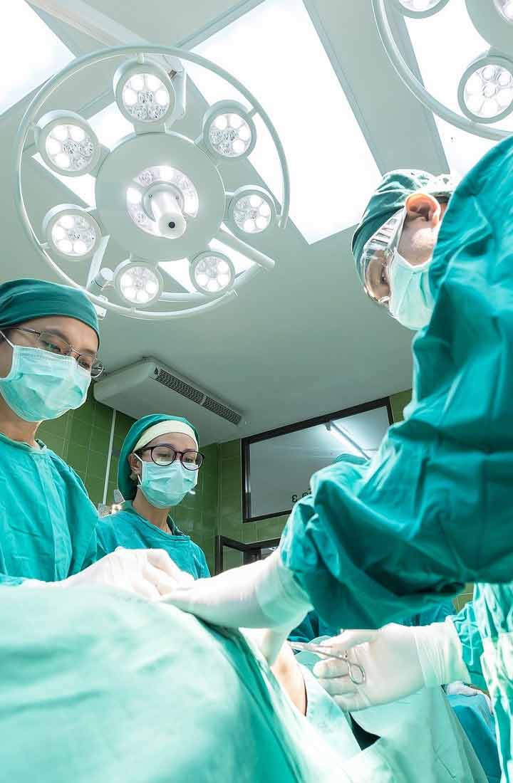 A trio of bemasked surgeons examining a subject