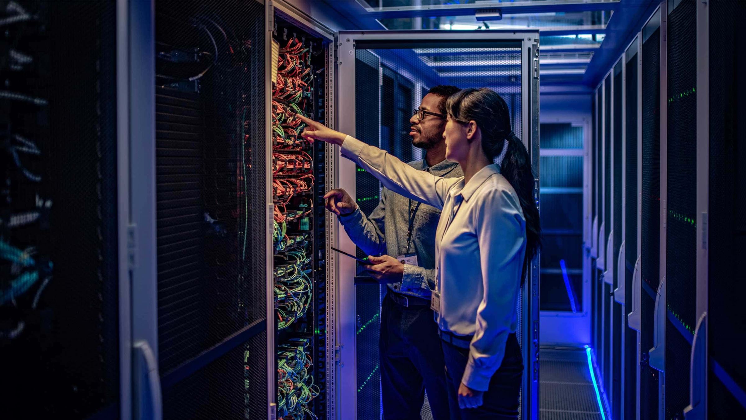 Two experts looking at racks in data centre