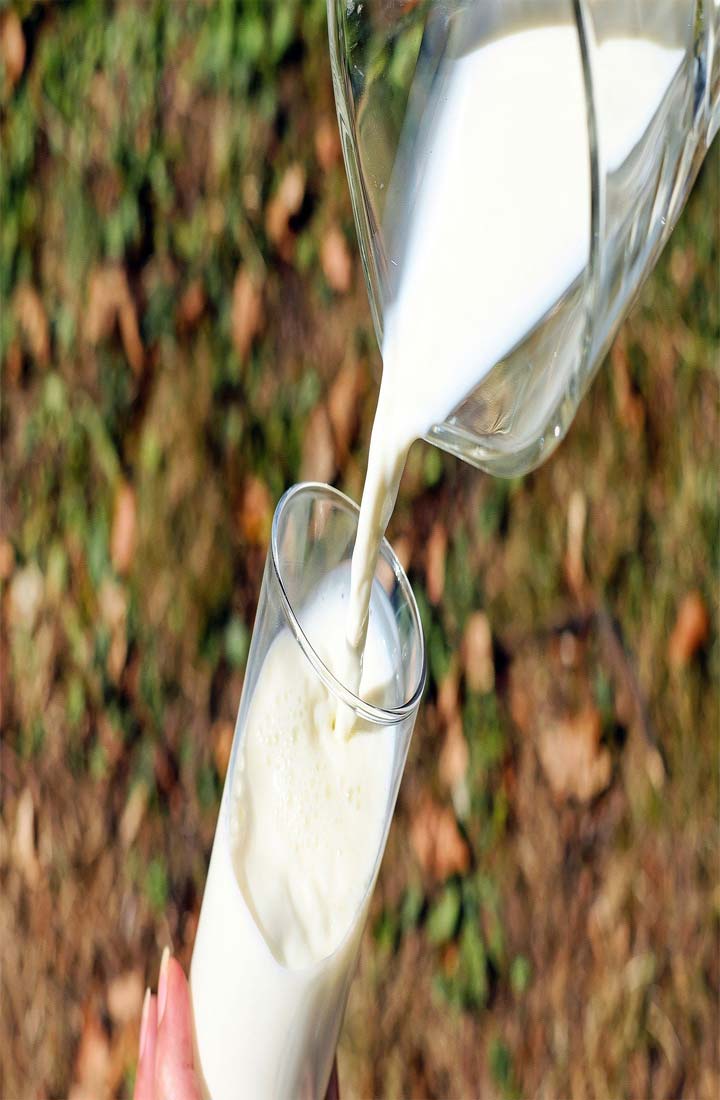 Een glas melk dat uit een glazen kan wordt geschonken, buiten