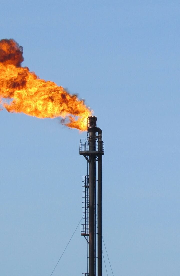 Oil and gas flare stack with blue sky backround close up and large flare flame